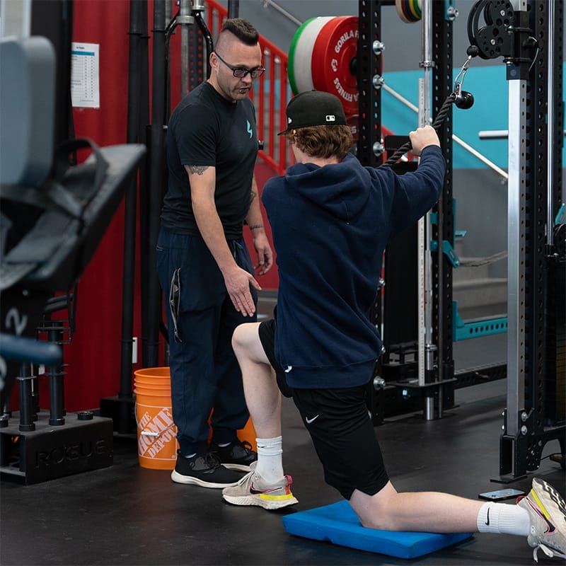 Young man exercising while a coach supervises at Speed Mechanics